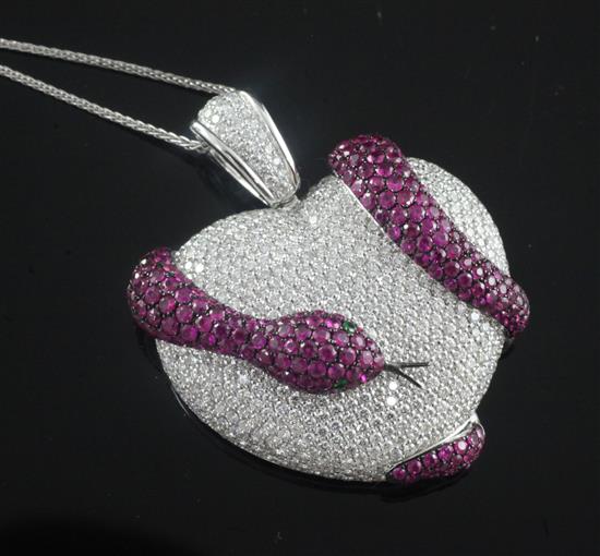 An 18ct white gold, pave set diamond, ruby set heart shaped pendant with entwined serpent, pendant 4.5cm.